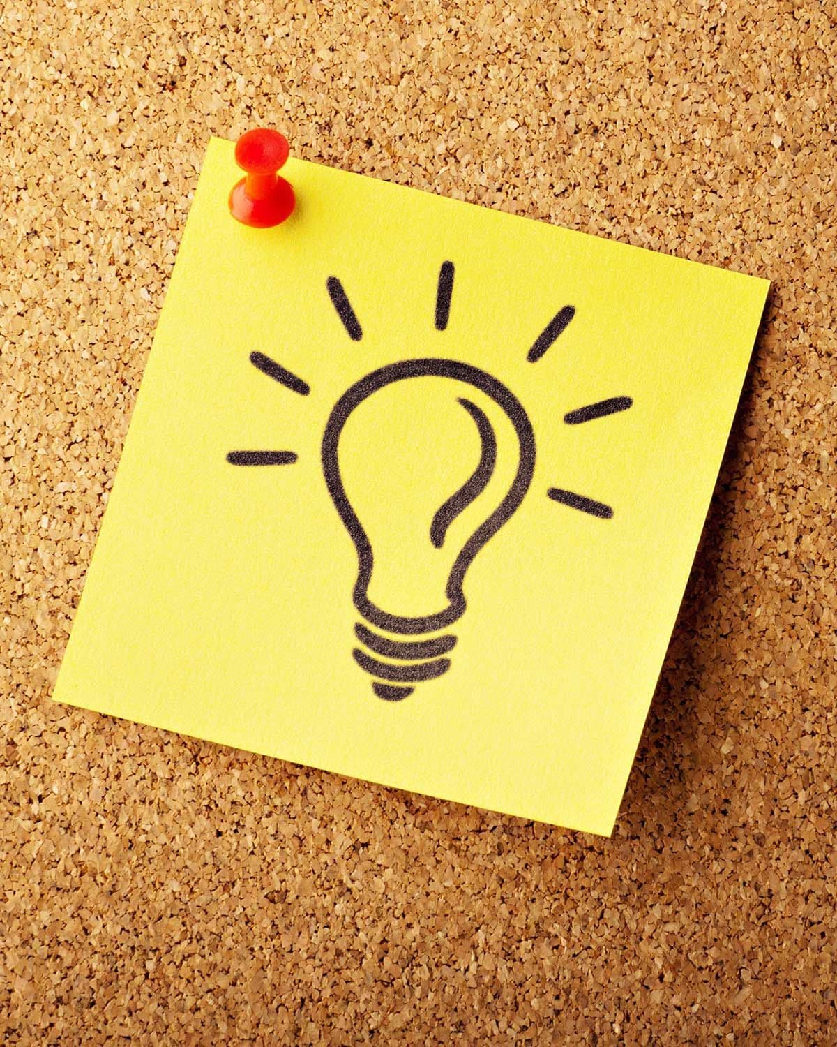 Eine Glühbirne auf einem Post-it gemalt, angeheftet an eine Pinnwand